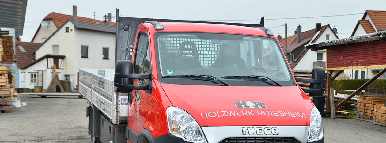 Rotes Lieferfahrzeug des Holzfachmarkts Rutesheim auf einem Parkplatz.